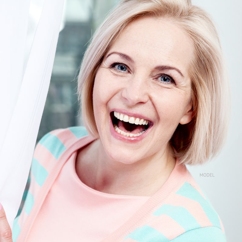 Middle-aged woman smiling with a bob haircut and a blue and pink striped sweater.