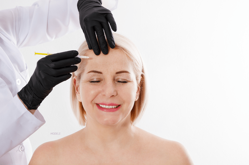 Woman getting a facial injection in forehead.