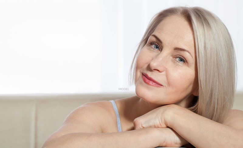 A pretty, middle-aged woman with hands crossed.