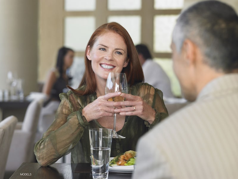 Middle-aged woman smiling and holding a glass of wine while on a date