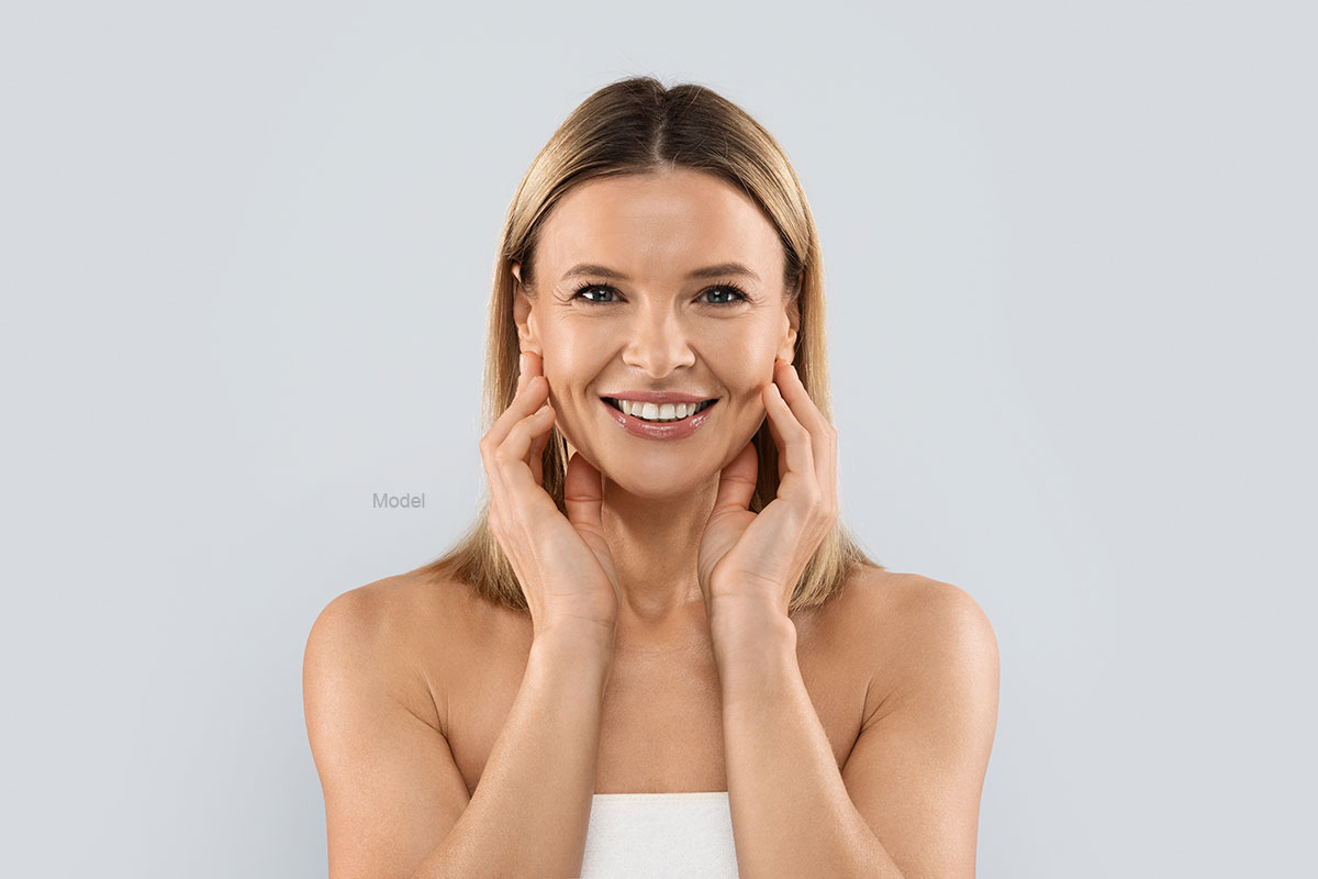 Blonde woman touches her face and smiles