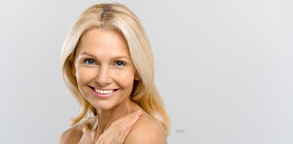 Woman looking in at front as she touches her shoulder 